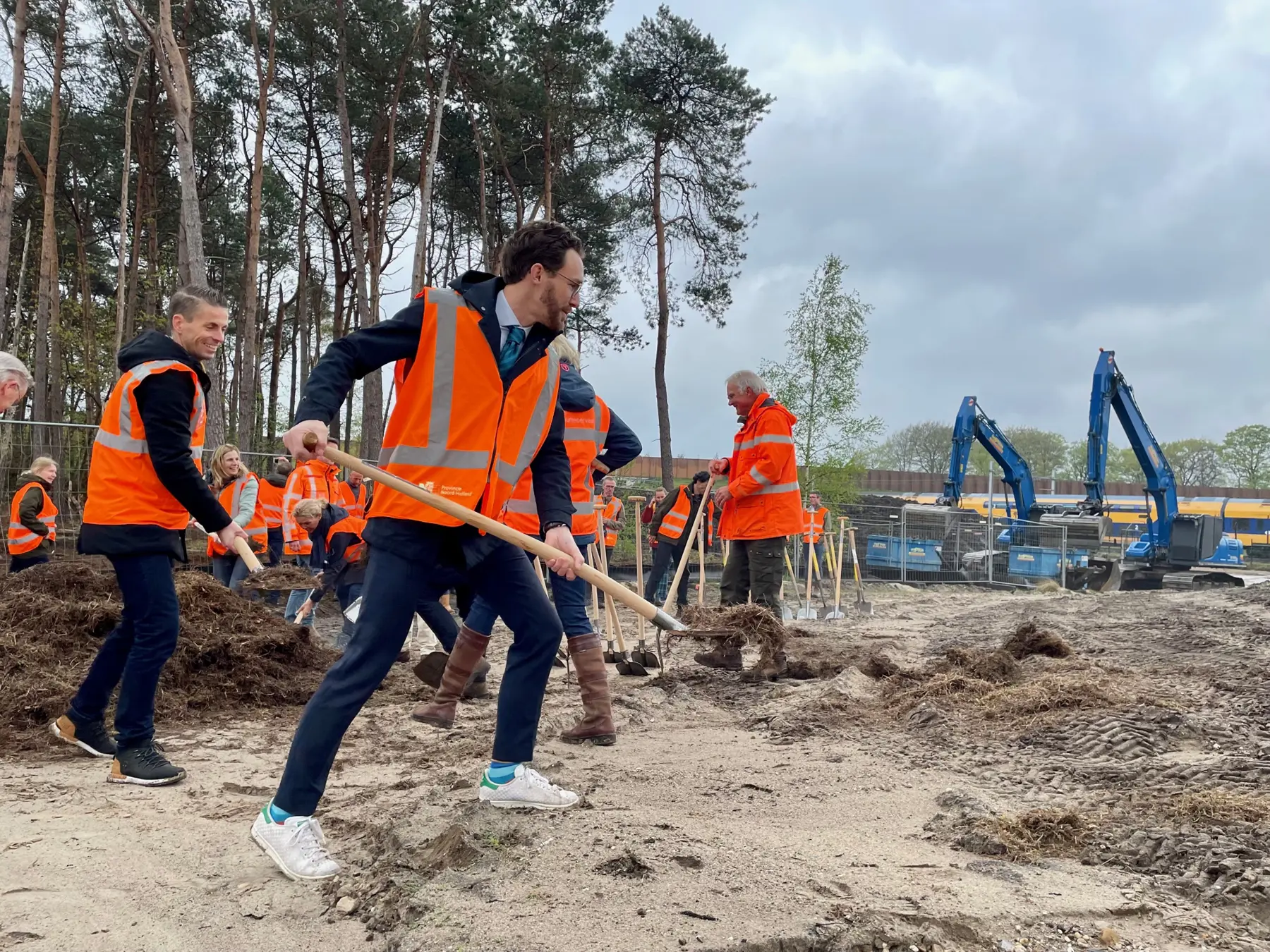 ProRail regiodirecteur Harro Homan (l) en wethouder Arno Scheepers  (midden) scheppen het laatste schepje heidemaaisel op de brug