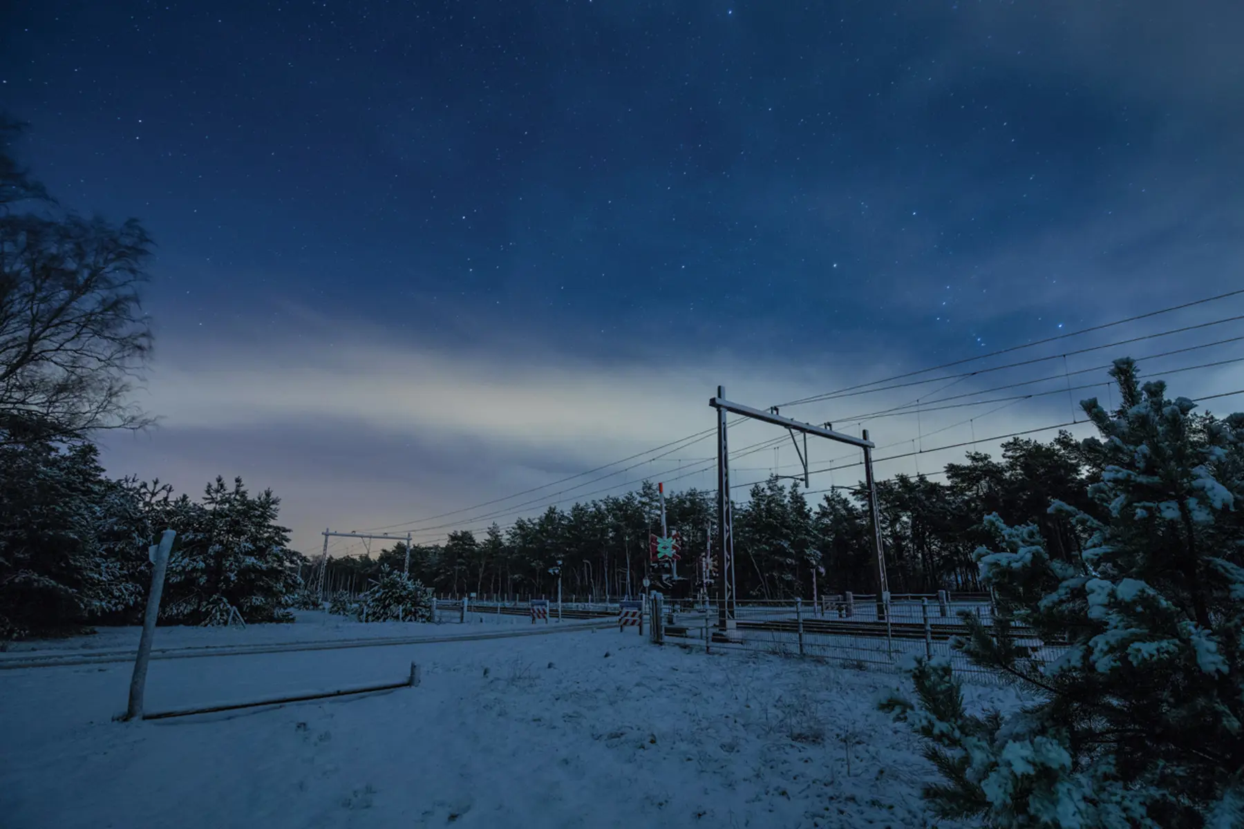 Een overweg in de sneeuw, in de nacht