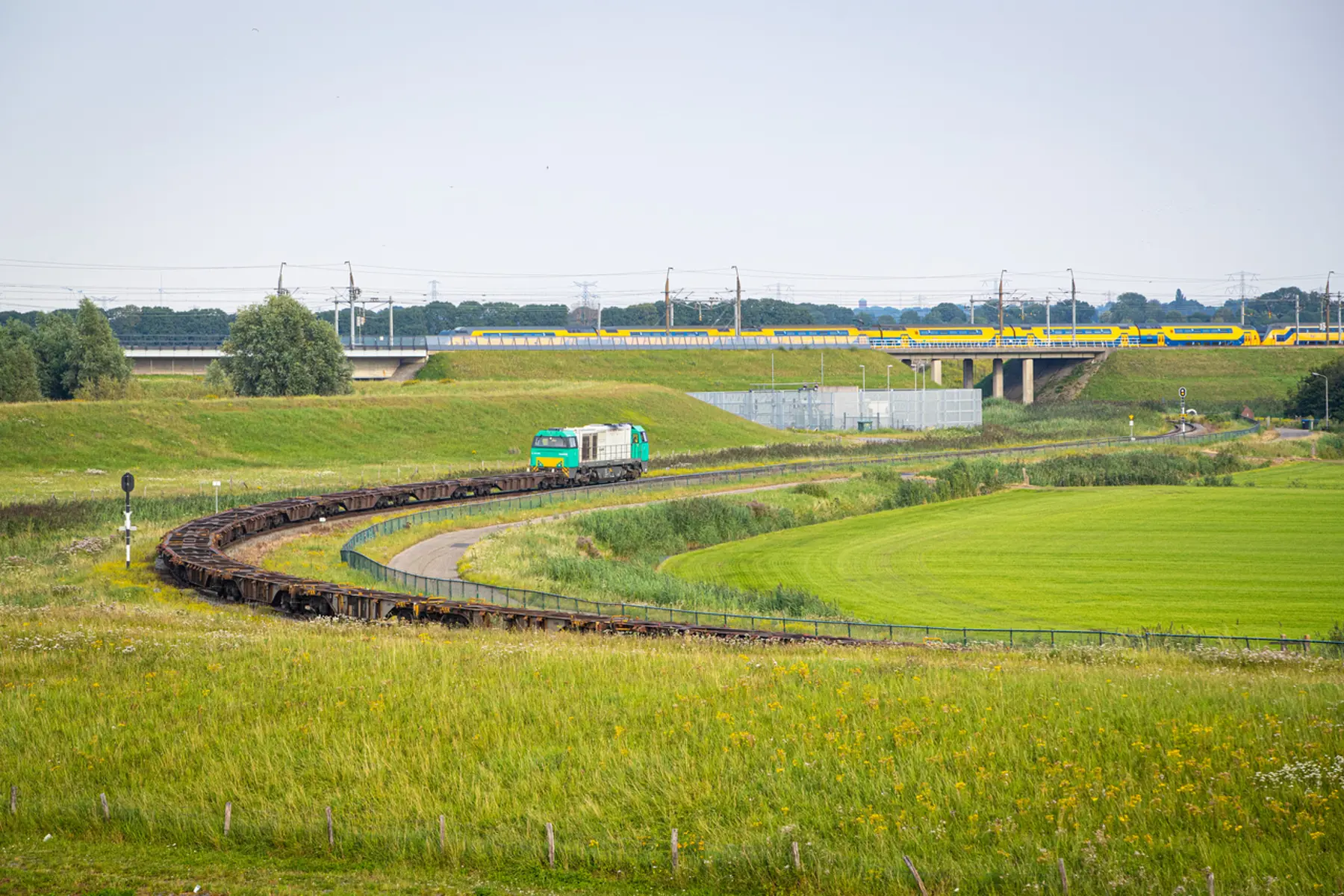 Goederentrein met lege containerwagens op een spoordijk